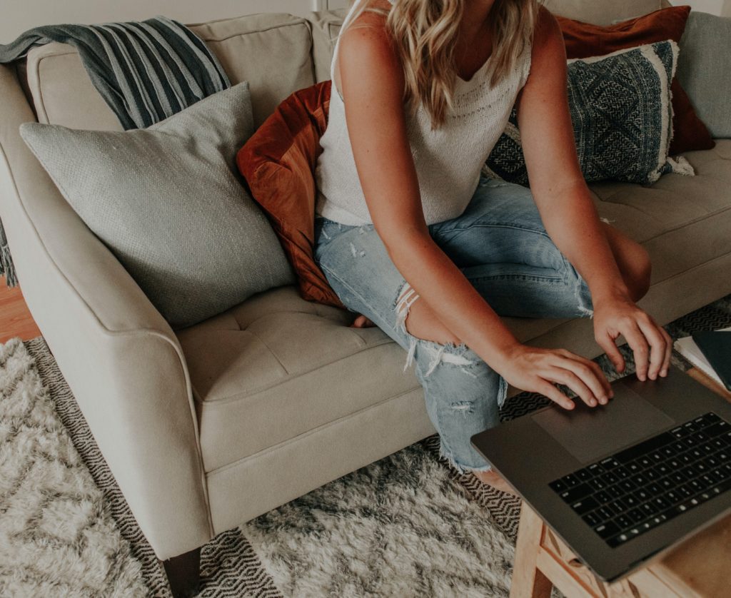 image of woman sitting on couch and using her laptop