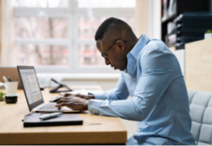 man with rounded shoulders at desk